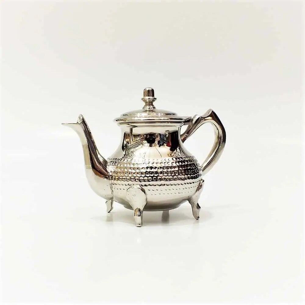 Wide oblate hammered teapot in silver finish with four cabriole feet and ornate spout on white background Wide oblate hammered teapot in silver finish with four cabriole feet and ornate spout on white background