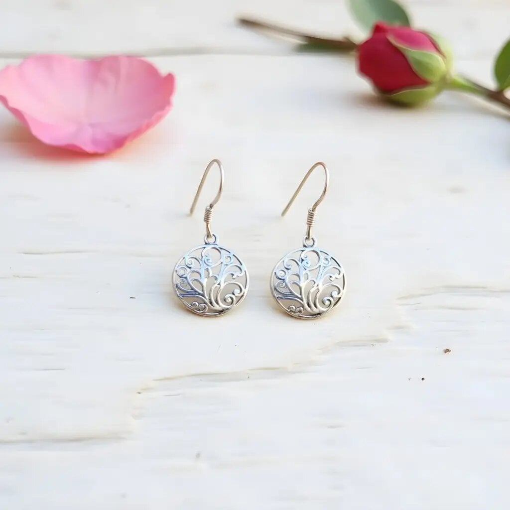 Sterling silver filigree earrings with Tree of Life design on white wood background with pink rose