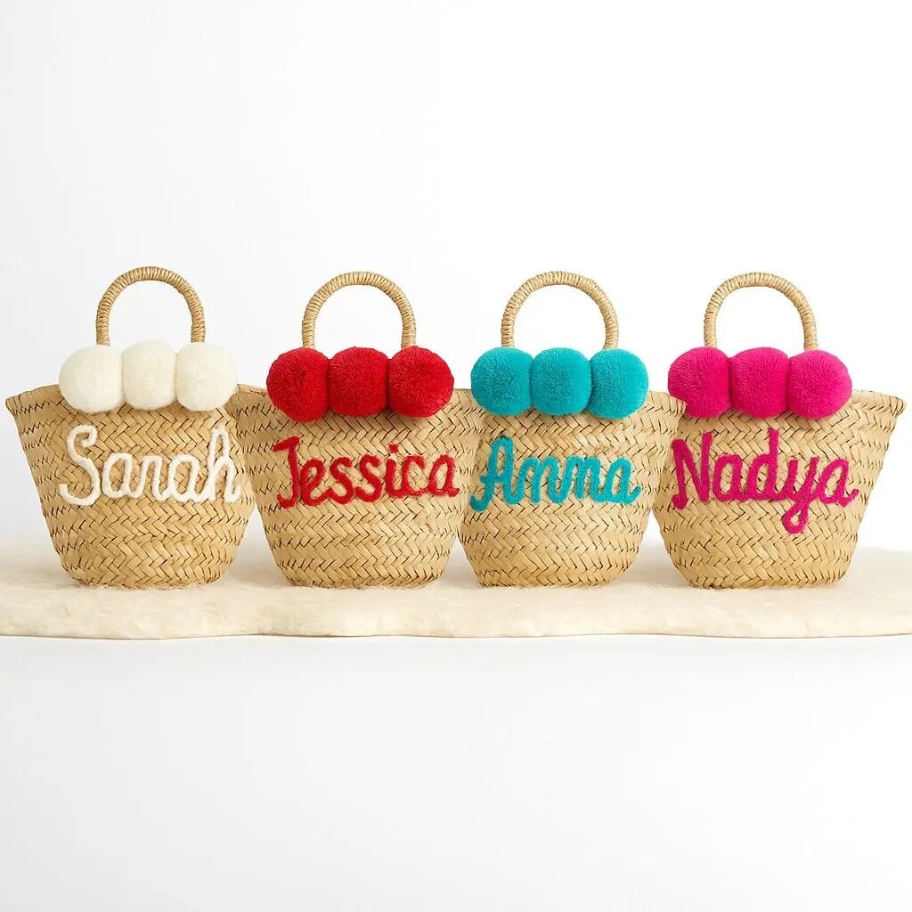 "Custom straw bag set of four with yarn-embroidered names Sarah Jessica Anna Nadya and colorful pom-pom accents on white fur" - that's about 117 chars ✓