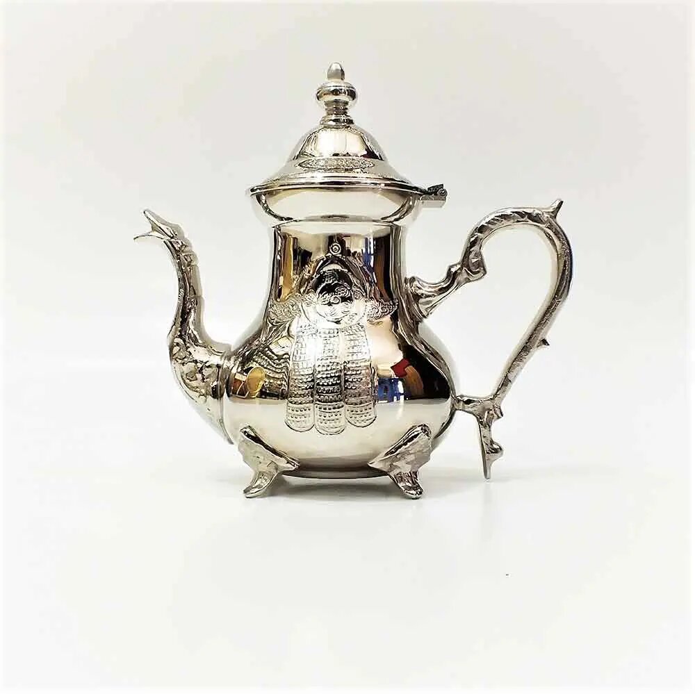 Hand-engraved hamsa grid silver teapot on plain background, tall narrow-waisted body with domed lid, curved spout, and o Hand-engraved hamsa grid silver teapot on plain background, tall narrow-waisted body with domed lid, curved spout, and ornate handle