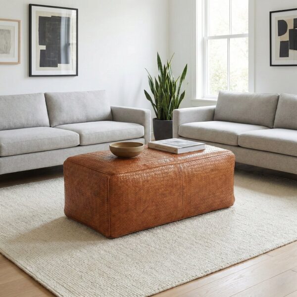 Light brown woven leather bench ottoman centered between grey sofas in modern living room Light brown woven leather bench ottoman centered between grey sofas in modern living room