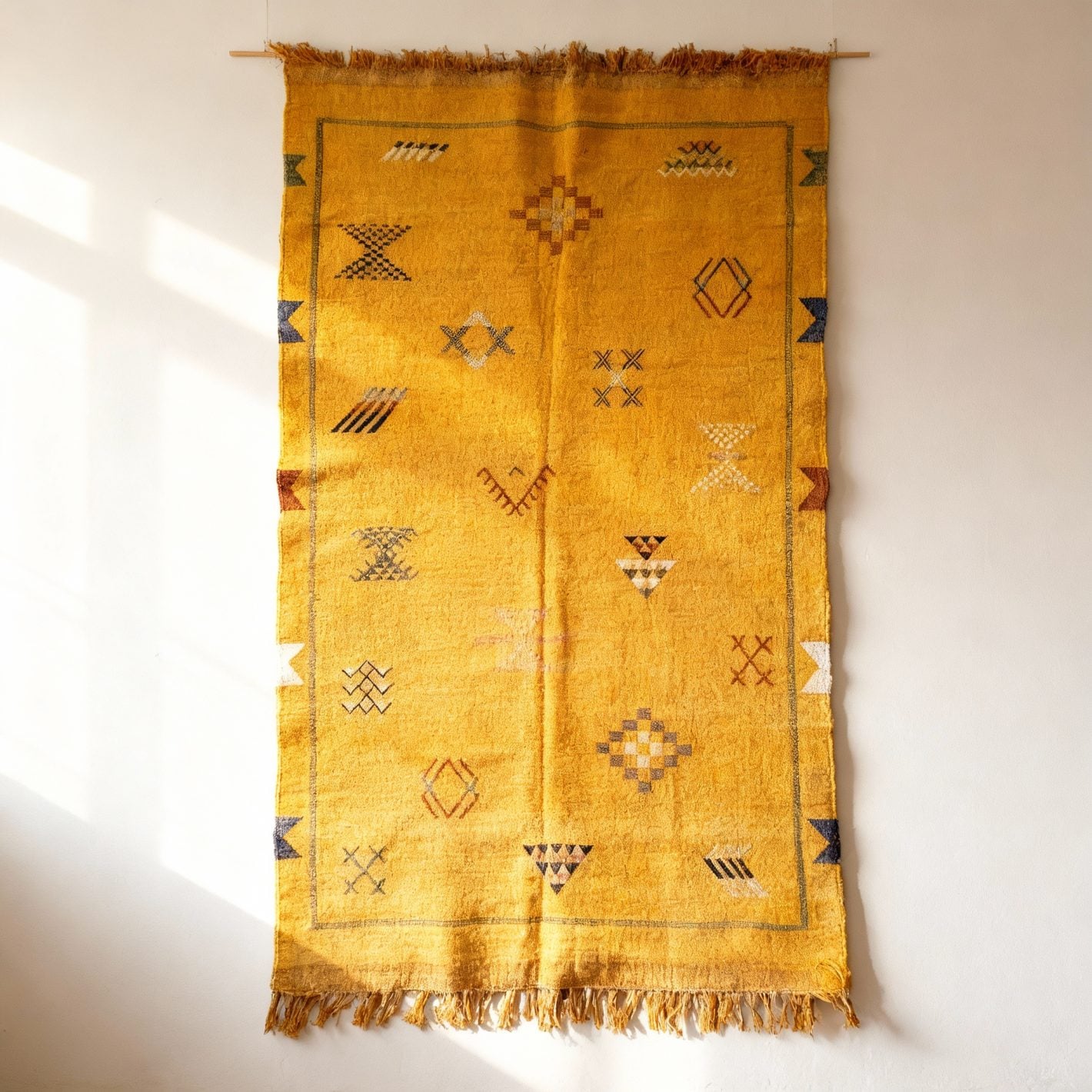 Yellow cactus silk rug hung on wall displaying traditional Berber geometric patterns and fringe tassels Yellow cactus silk rug hung on wall displaying traditional Berber geometric patterns and fringe tassels