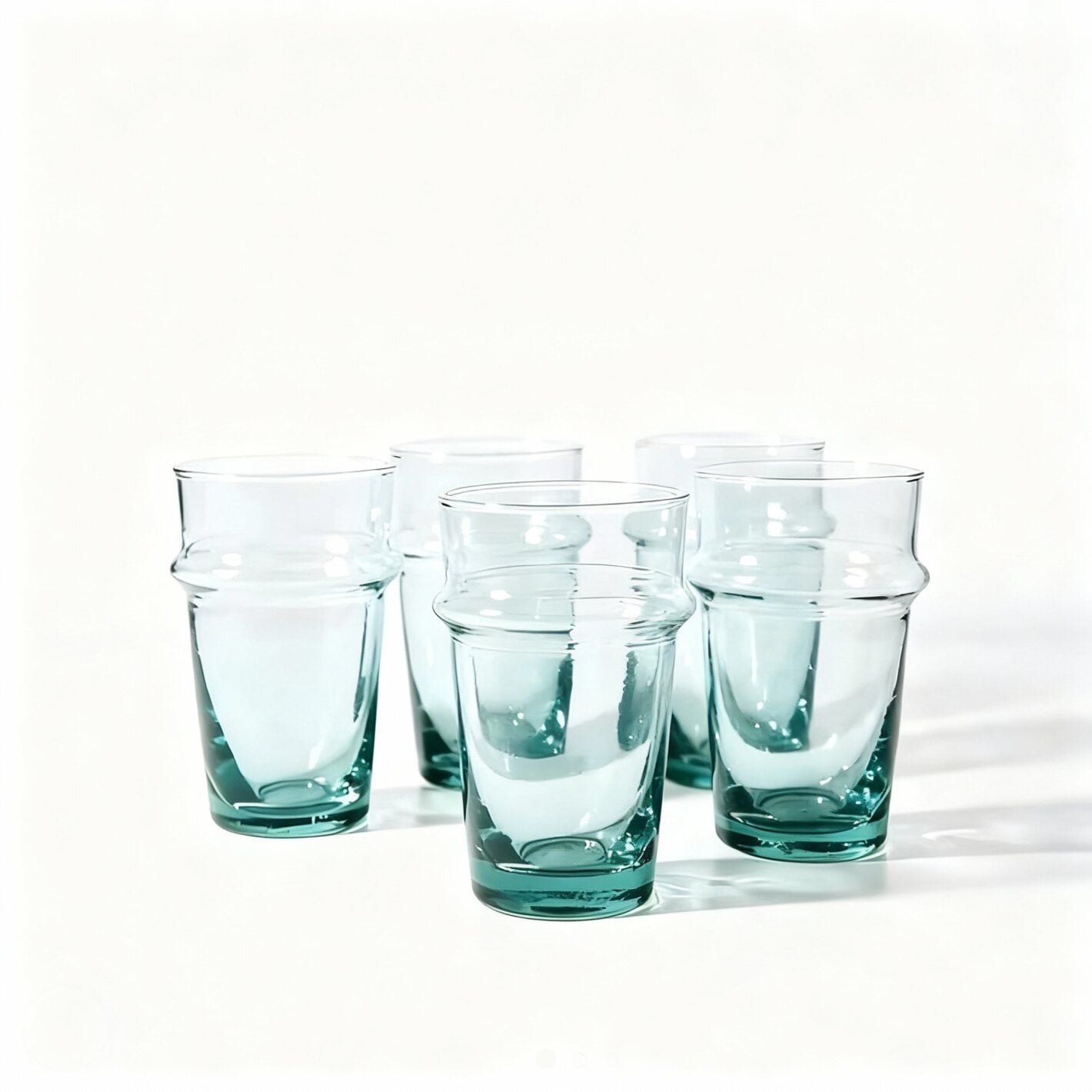Three transparent aqua beldi tea glasses with handblown texture on white background Three transparent aqua beldi tea glasses with handblown texture on white background