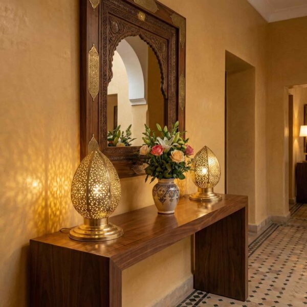 Pair of brass filigree table lamps flanking ornate mirror on entryway console creating ambient lighting Pair of brass filigree table lamps flanking ornate mirror on entryway console creating ambient lighting