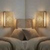 Pair of brass mandala wall lights flanking bed headboard casting radial shadow patterns across bedroom walls