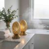 Pair of brass oval table lamps on marble bathroom counter creating spa-like ambient lighting