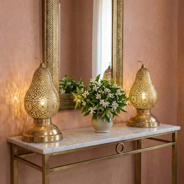 Two brass pear table lamps on marble console table with flowers casting decorative shadow patterns on pink wall Two brass pear table lamps on marble console table with flowers casting decorative shadow patterns on pink wall