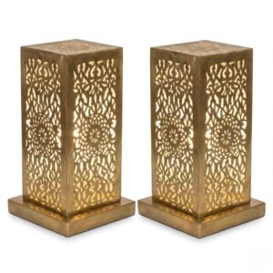 Pair of hand-engraved perforated brass table lamps with geometric floral patterns glowing warmly against white background