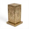 Single perforated brass table lamp showing intricate hand-engraved geometric and floral cutout patterns with warm interi Single perforated brass table lamp showing intricate hand-engraved geometric and floral cutout patterns with warm interior glow