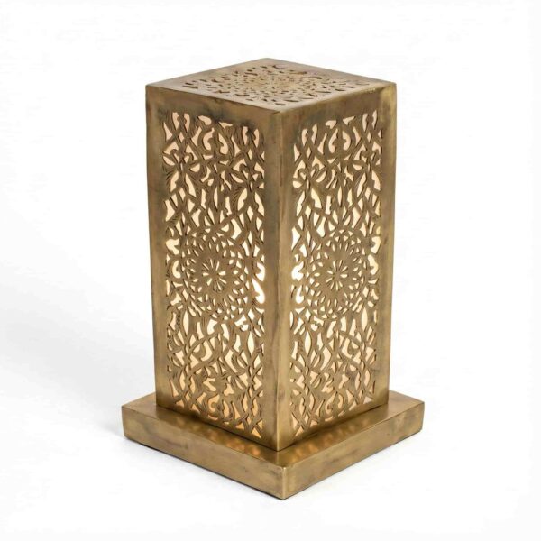 Single perforated brass table lamp showing intricate hand-engraved geometric and floral cutout patterns with warm interi Single perforated brass table lamp showing intricate hand-engraved geometric and floral cutout patterns with warm interior glow