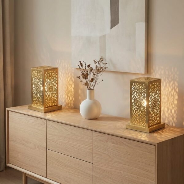 Perforated brass table lamps on modern oak sideboard casting warm ambient shadows alongside ceramic vase and dried flowe Perforated brass table lamps on modern oak sideboard casting warm ambient shadows alongside ceramic vase and dried flowers