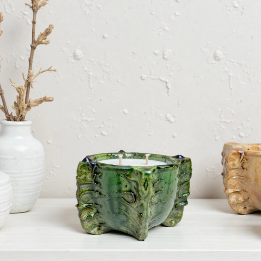 Green ceramic candle 10 inch bowl with triple wicks and sculptural leaf design on white shelf Green ceramic candle 10 inch bowl with triple wicks and sculptural leaf design on white shelf