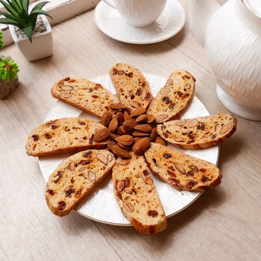 Moroccan fekkas cookies with almonds and raisins arranged in flower pattern on white plate with coffee cup