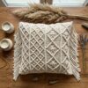 Handwoven macrame cushion cover with diamond knotwork pattern and fringe displayed on wooden table with candles and drie Handwoven macrame cushion cover with diamond knotwork pattern and fringe displayed on wooden table with candles and dried lavender