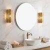 Moroccan brass filigree wall sconce mounted in luxury marble bathroom beside round mirror Moroccan brass filigree wall sconce mounted in luxury marble bathroom beside round mirror