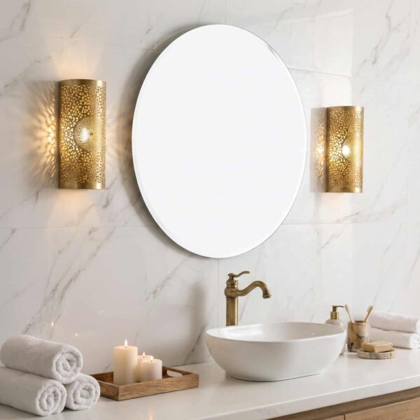 Moroccan brass filigree wall sconce mounted in luxury marble bathroom beside round mirror Moroccan brass filigree wall sconce mounted in luxury marble bathroom beside round mirror