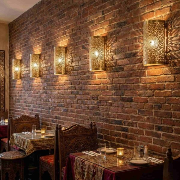 Row of Moroccan brass filigree wall sconces illuminating exposed brick wall in restaurant Row of Moroccan brass filigree wall sconces illuminating exposed brick wall in restaurant