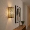 Moroccan brass filigree wall light casting intricate lace shadow patterns in modern hallway