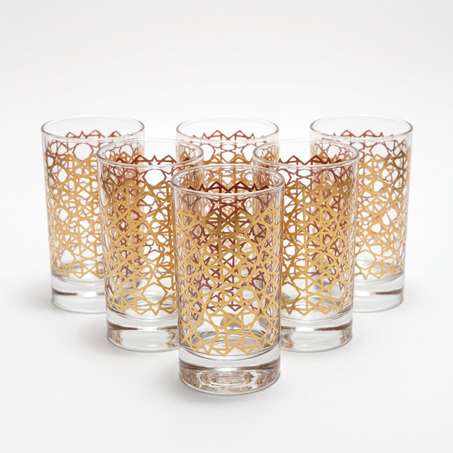 Set of six gold ombré Moroccan tea glasses featuring a geometric lattice pattern on clear glass, arranged on a white bac Set of six gold ombré Moroccan tea glasses featuring a geometric lattice pattern on clear glass, arranged on a white background.