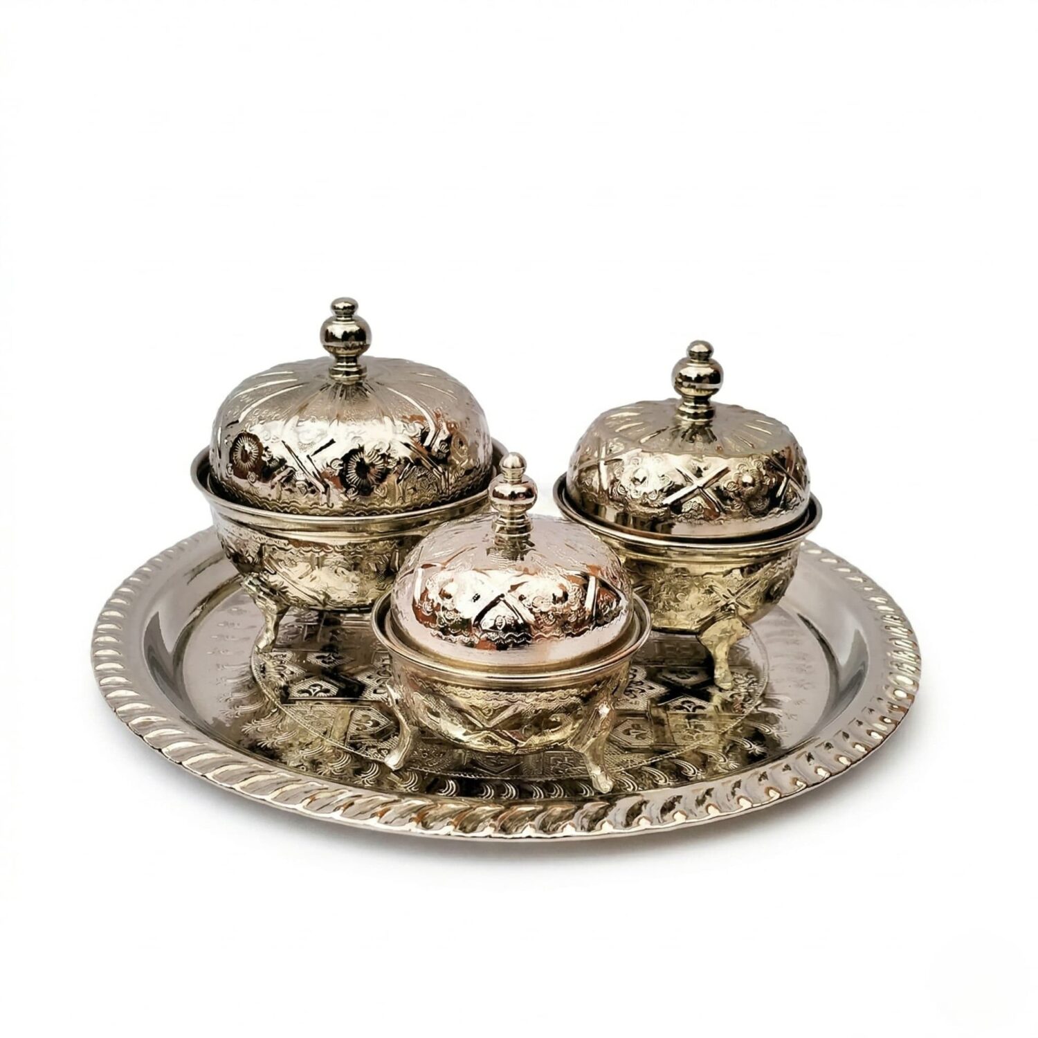 Hand-embossed silver tea container set with three graduated footed bowls on an ornate round tray, studio shot on white Hand-embossed silver tea container set with three graduated footed bowls on an ornate round tray, studio shot on white
