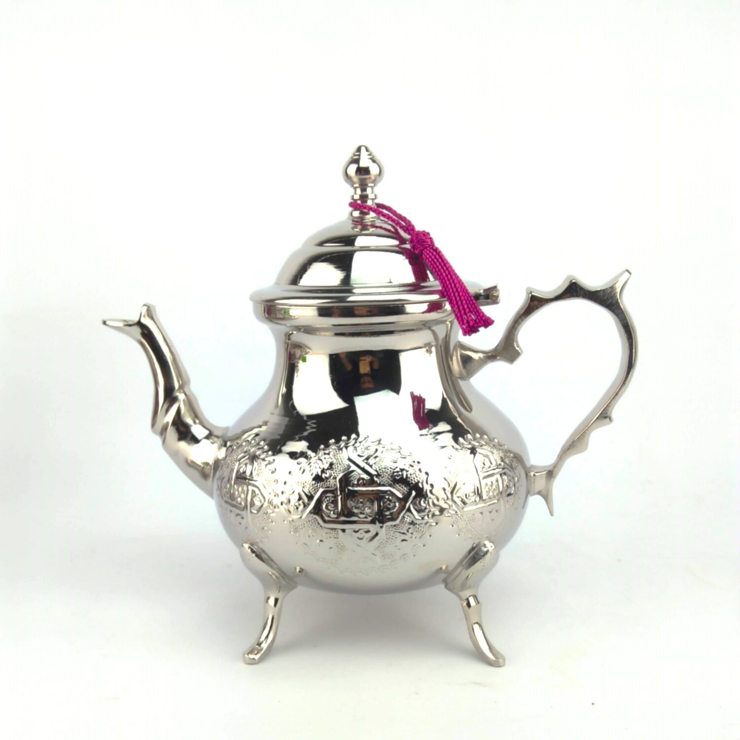 Extra large engraved silver teapot with hand-engraved geometric motifs, domed lid with pink tassel, and footed base on w Extra large engraved silver teapot with hand-engraved geometric motifs, domed lid with pink tassel, and footed base on white background
