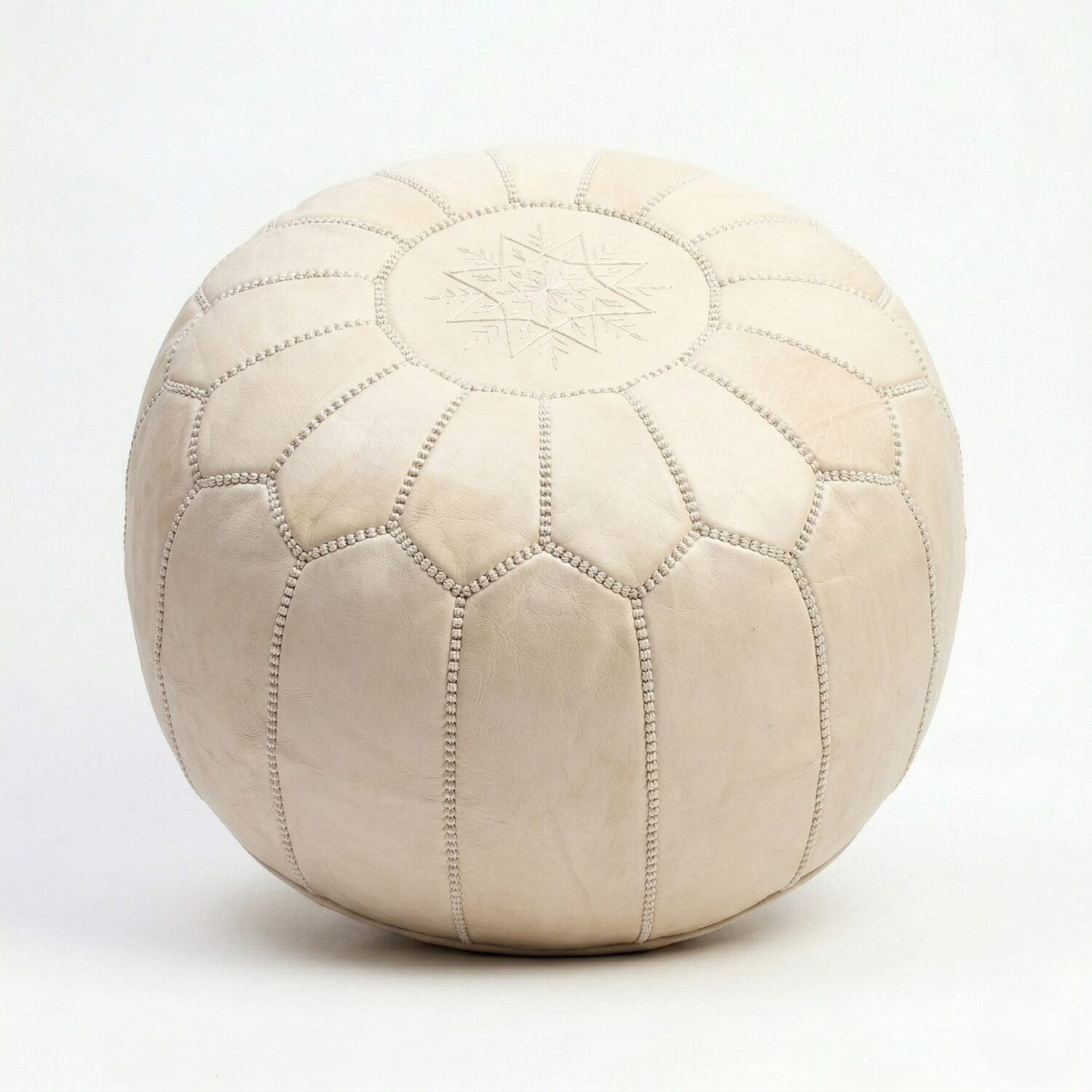 Handcrafted undyed genuine leather pouf in natural tan with embroidered geometric star motif on white studio background