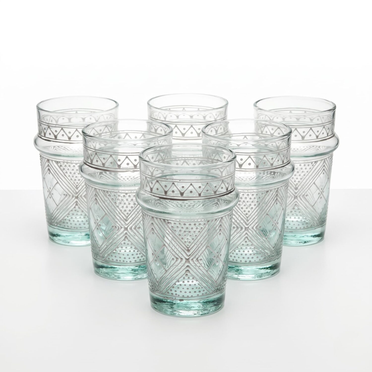 Set of six white geometric tea glasses with hand-painted patterns, arranged in a pyramid on a white studio background Set of six white geometric tea glasses with hand-painted patterns, arranged in a pyramid on a white studio background
