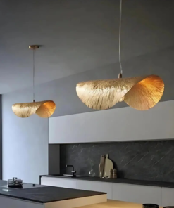 Two hammered brass leaf pendant lights glowing above a modern dark kitchen island