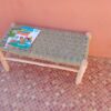 Handwoven doum palm rope bench with natural eucalyptus branch legs against a terracotta wall