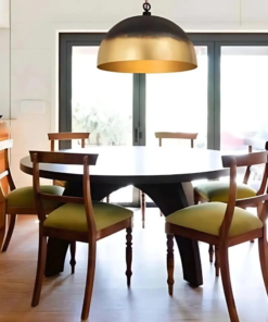 Large brass dome pendant hanging above a round dining table with wooden chairs