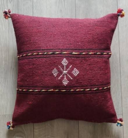 Handwoven Moroccan kilim pillow cover in burgundy with Berber motif and pompom corners