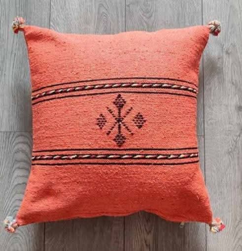 Handwoven Moroccan kilim pillow cover in coral with Berber motif and pompom corners