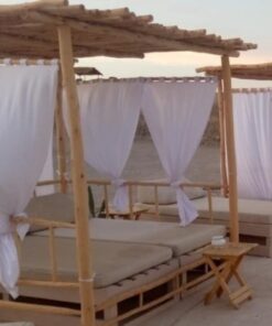 Eucalyptus baldaquin daybeds with white curtains on a beach terrace