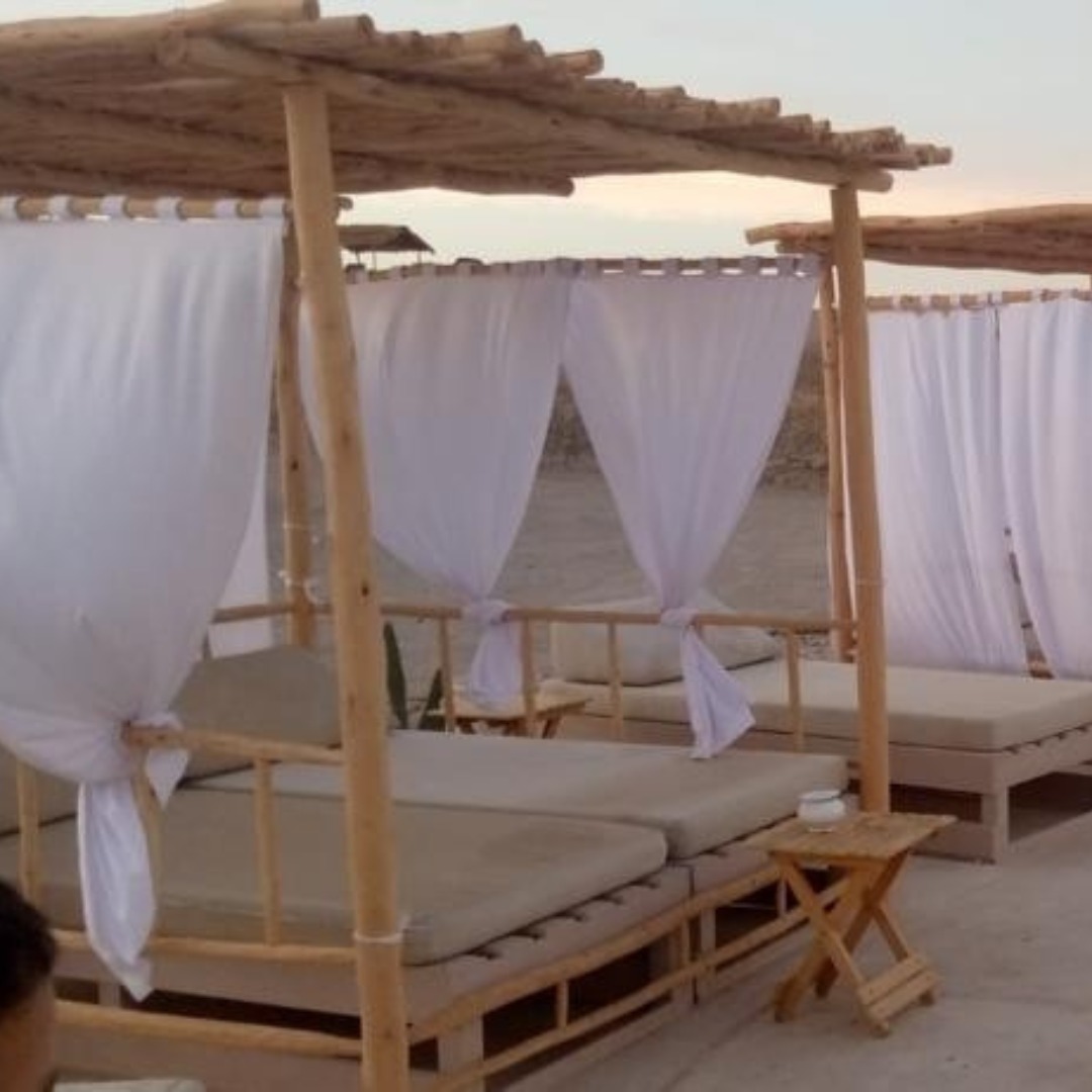 Eucalyptus baldaquin daybeds with white curtains on a beach terrace