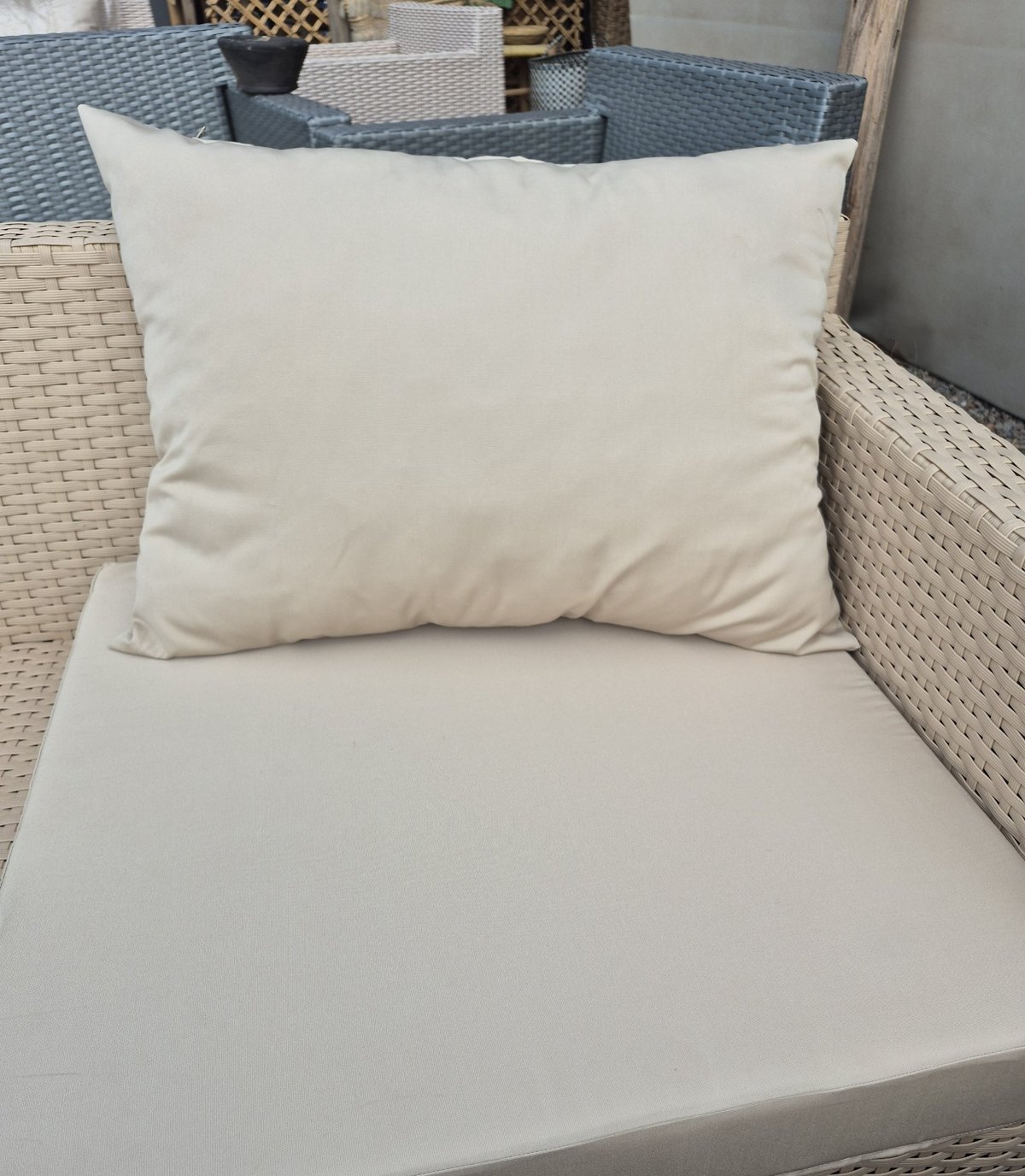 Sand beige water-resistant outdoor cushion on a rattan garden armchair