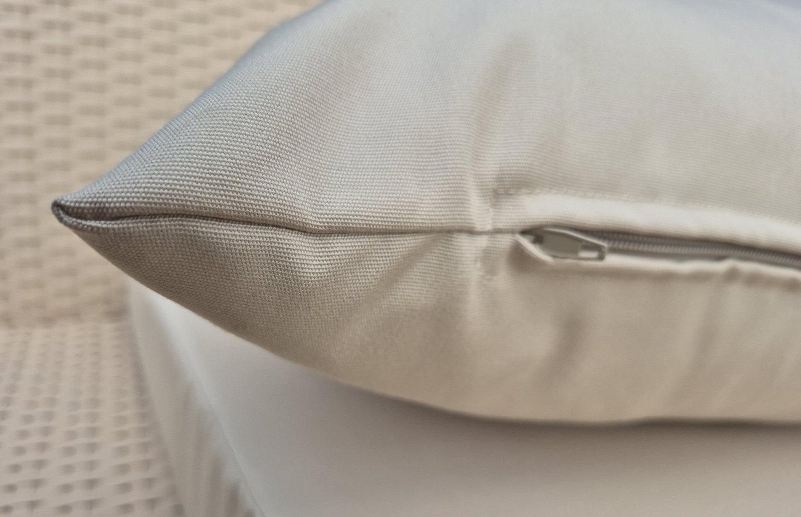Close-up of the concealed zip on a beige outdoor canvas cushion