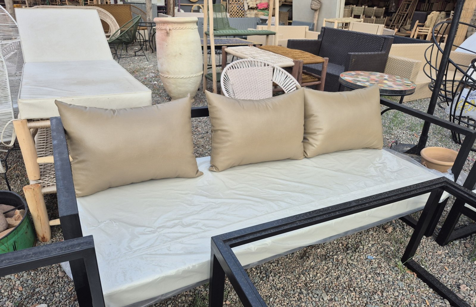 Taupe faux leather outdoor cushions on a black metal garden sofa