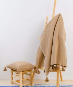 Sand beige Moroccan pom pom throw on a wooden ladder with a matching cushion on a stool
