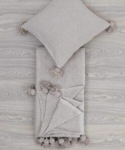 Folded light grey pom pom throw with a matching cushion cover