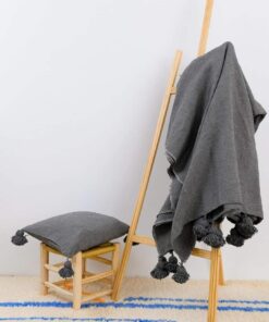 Charcoal grey Moroccan pom pom throw on a ladder with a matching cushion