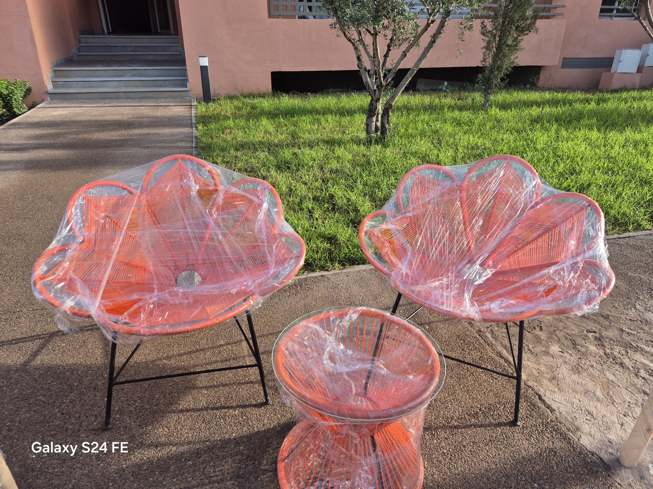 Pair of orange Moroccan flower-shaped rope lounge chairs with a matching rope side table in a Marrakech garden
