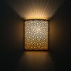 Moroccan brass wall sconce glowing warmly with rays of light fanning up and down the wall
