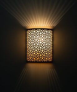 Moroccan brass wall sconce glowing warmly with rays of light fanning up and down the wall