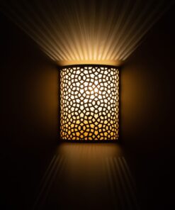 Brass wall light with Moroccan star pattern lit in a dark room