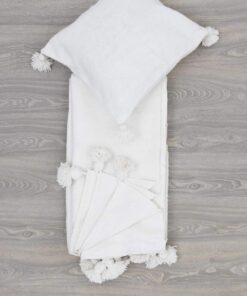 Folded ivory white pom pom throw with a matching cushion cover